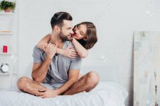 117877809-adult-couple-hugging-and-sitting-on-bed-with-white-bedding.jpg
